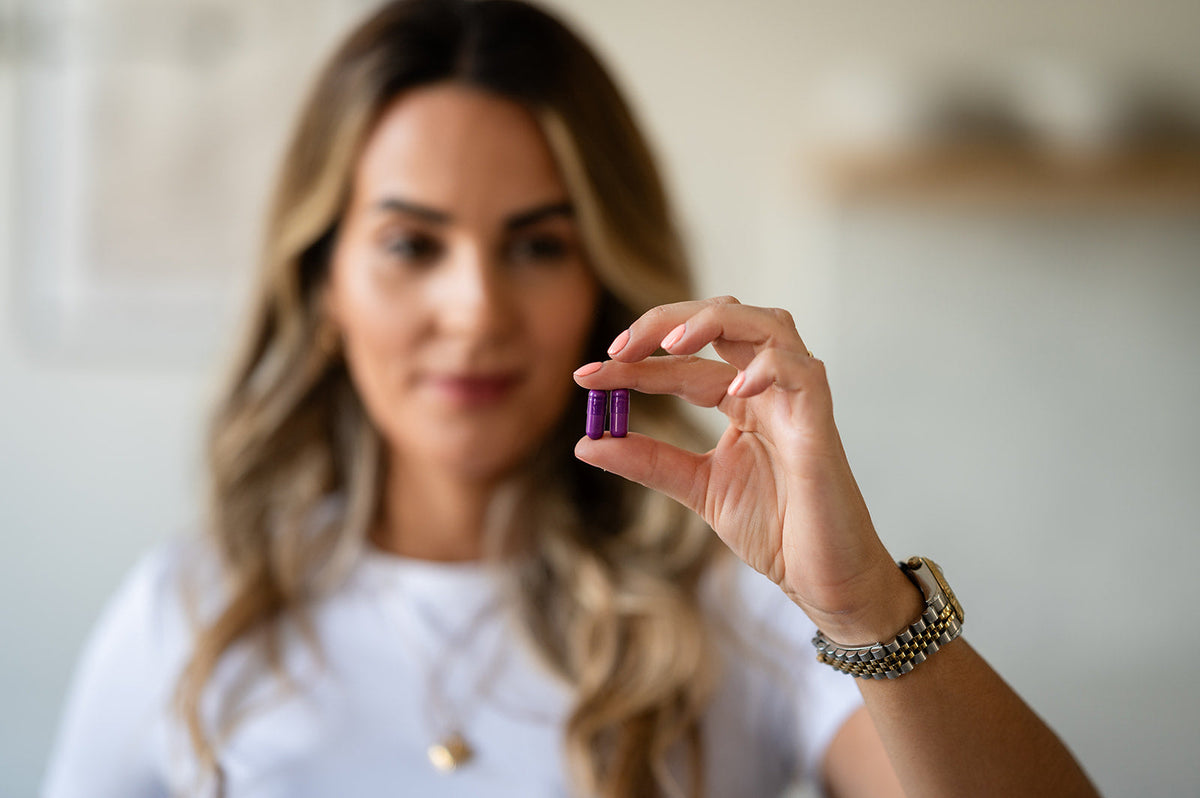 A woman holding supplement capsules